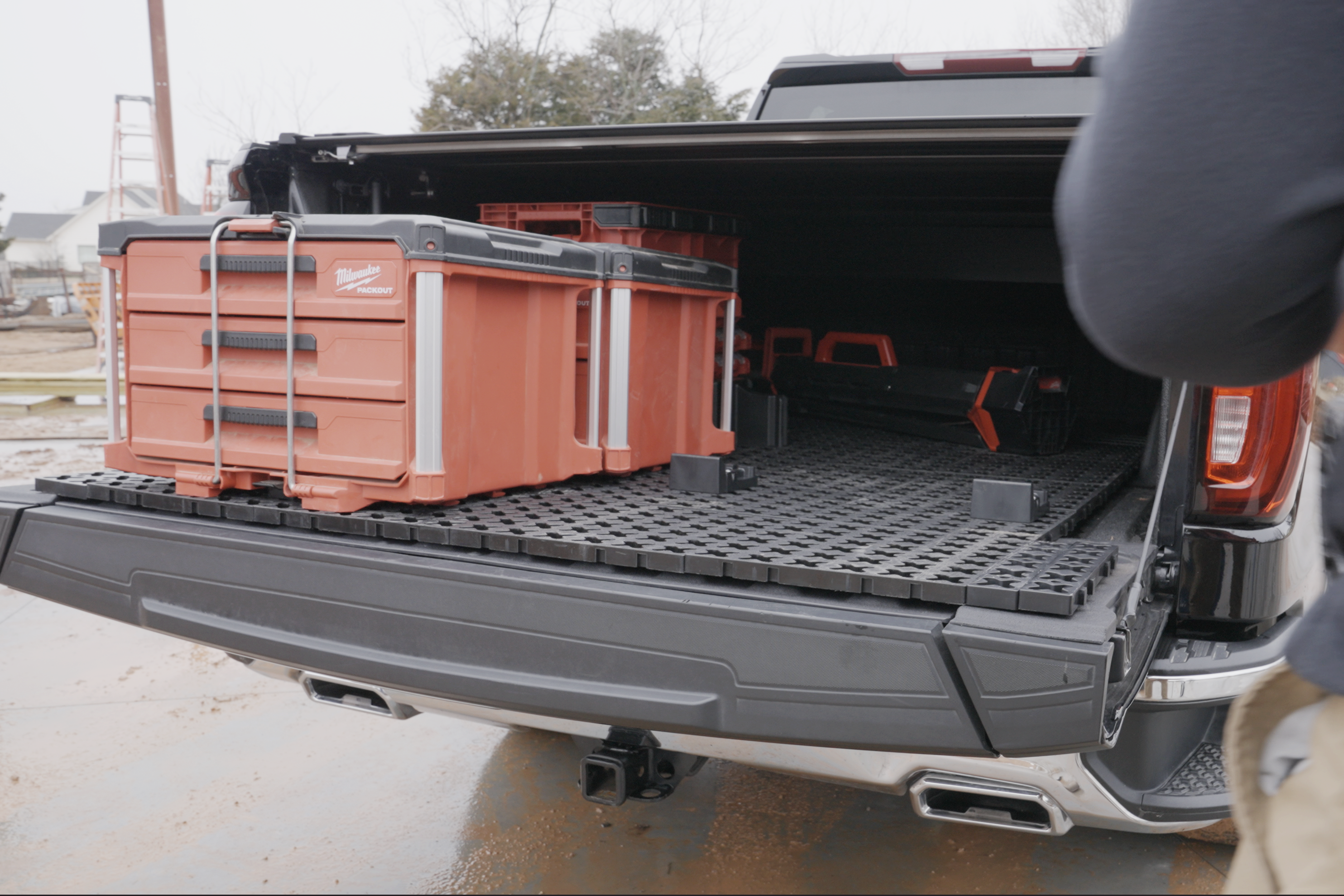 A Tmat truck bed mat slid onto a tailgate for unloading toolboxes on a job site.