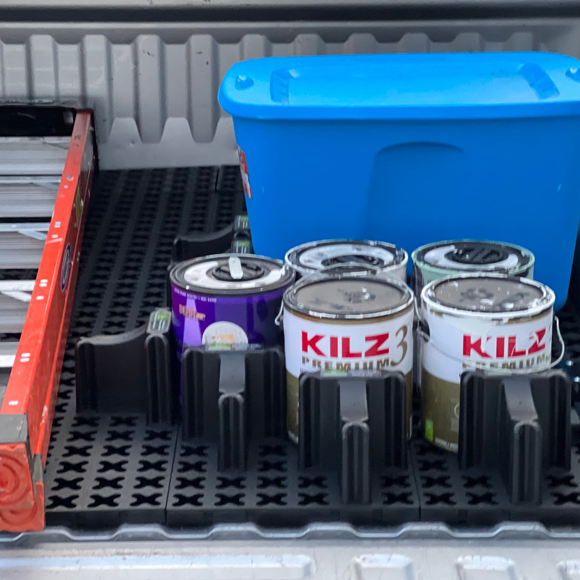 Paint cans and a ladder secured in the back of a pickup with a Tmat cargo system.