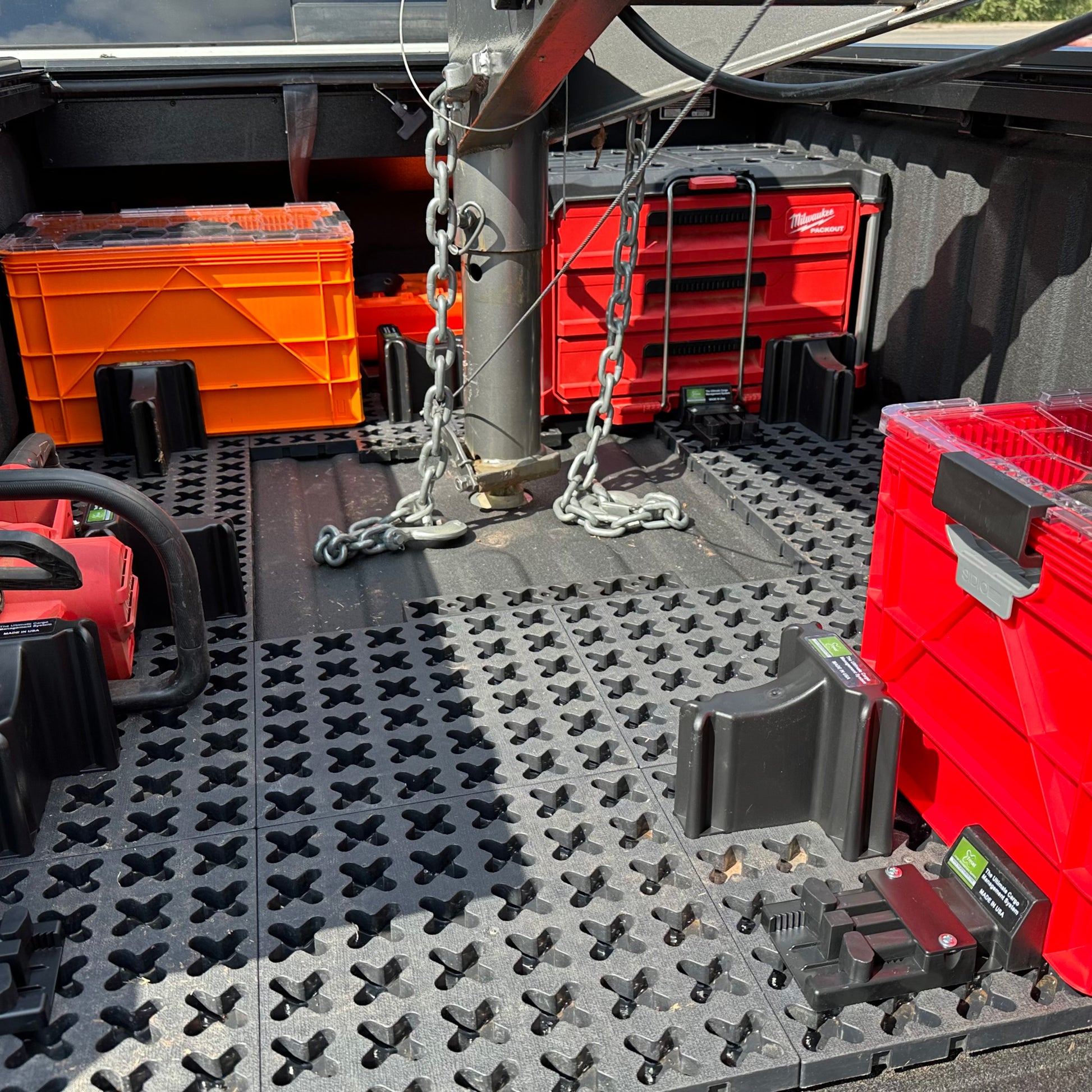 A chainsaw, Sidio storage crate, and red toolboxes secured in a truck bed with a gooseneck stock trailer attached.