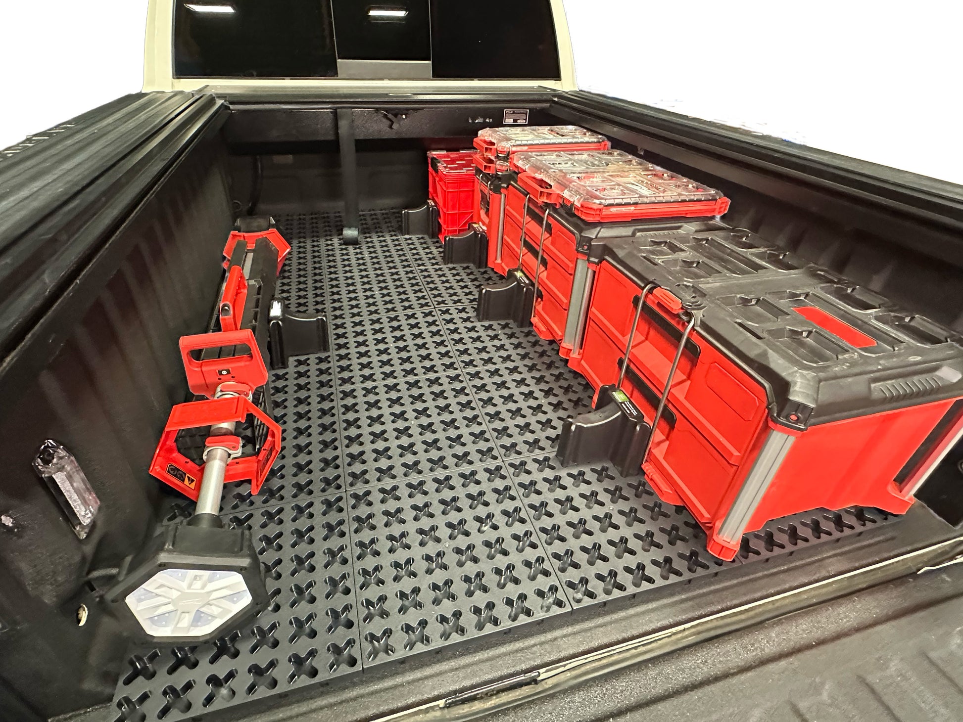 Tmat in a truck bed with Milwaukee Packout toolboxes, a red milk crate, and a shop light.