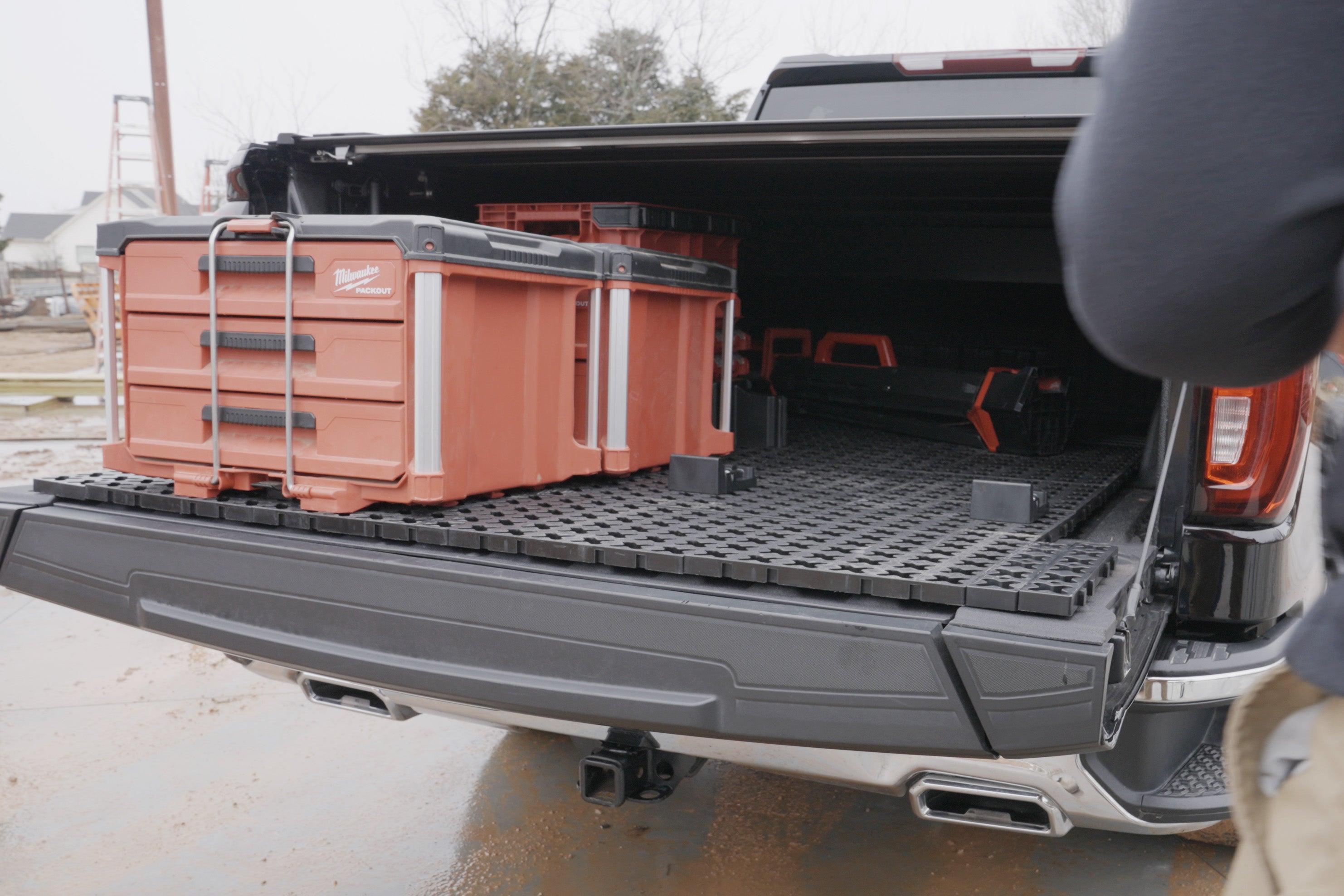 A Tmat truck bed mat slid onto a tailgate for unloading toolboxes on a job site.